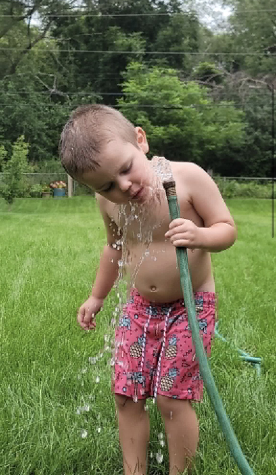 Grayson playing with a garden hose in the backyard