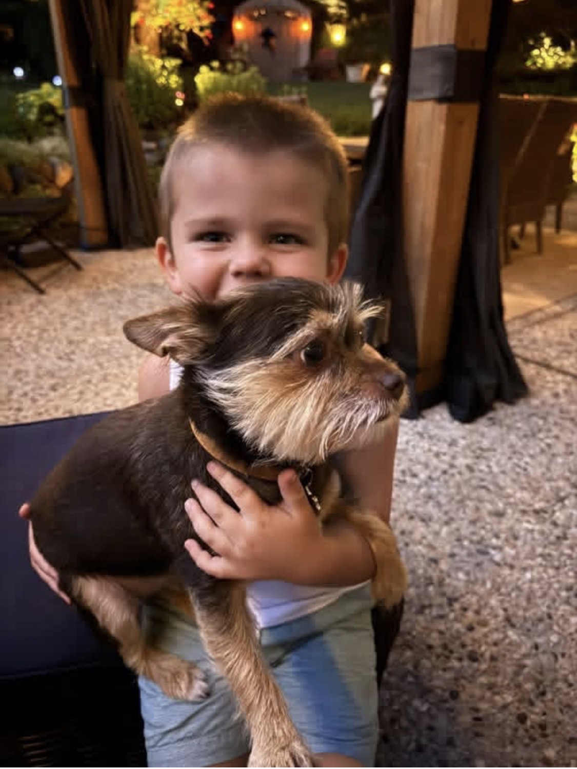 Grayson smiling while hugging a small dog