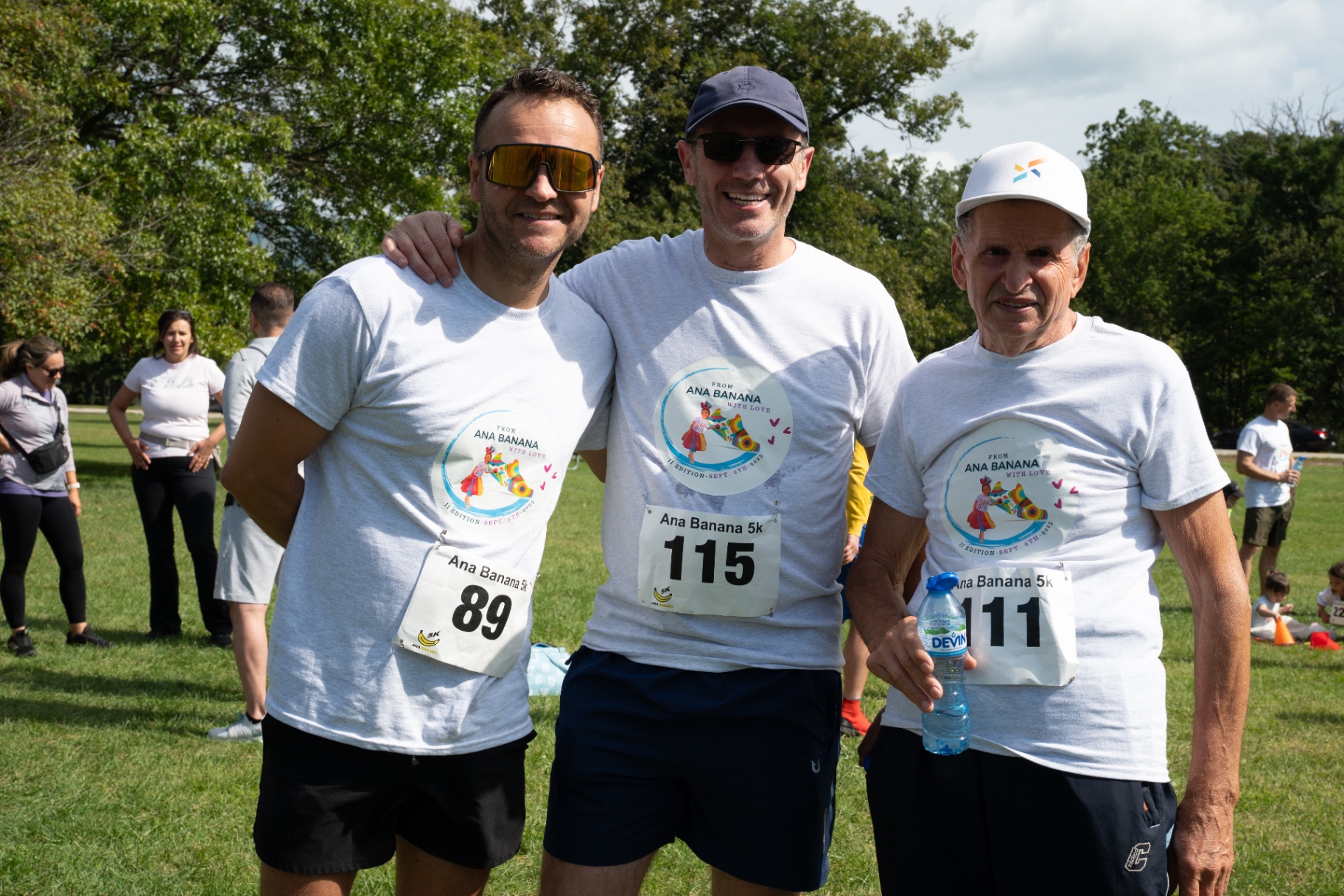 Three runners with race bibs smiling together