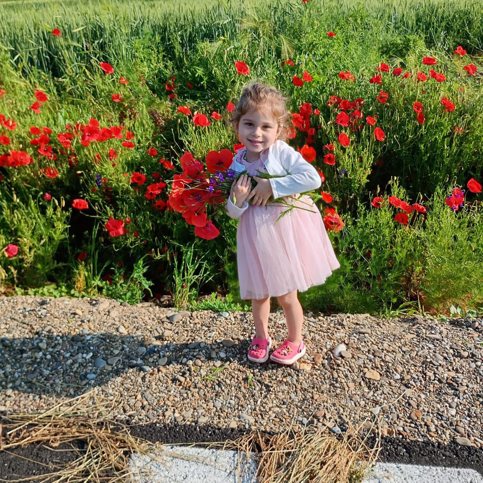 Carla standing in front of a field of red poppies holding flowers